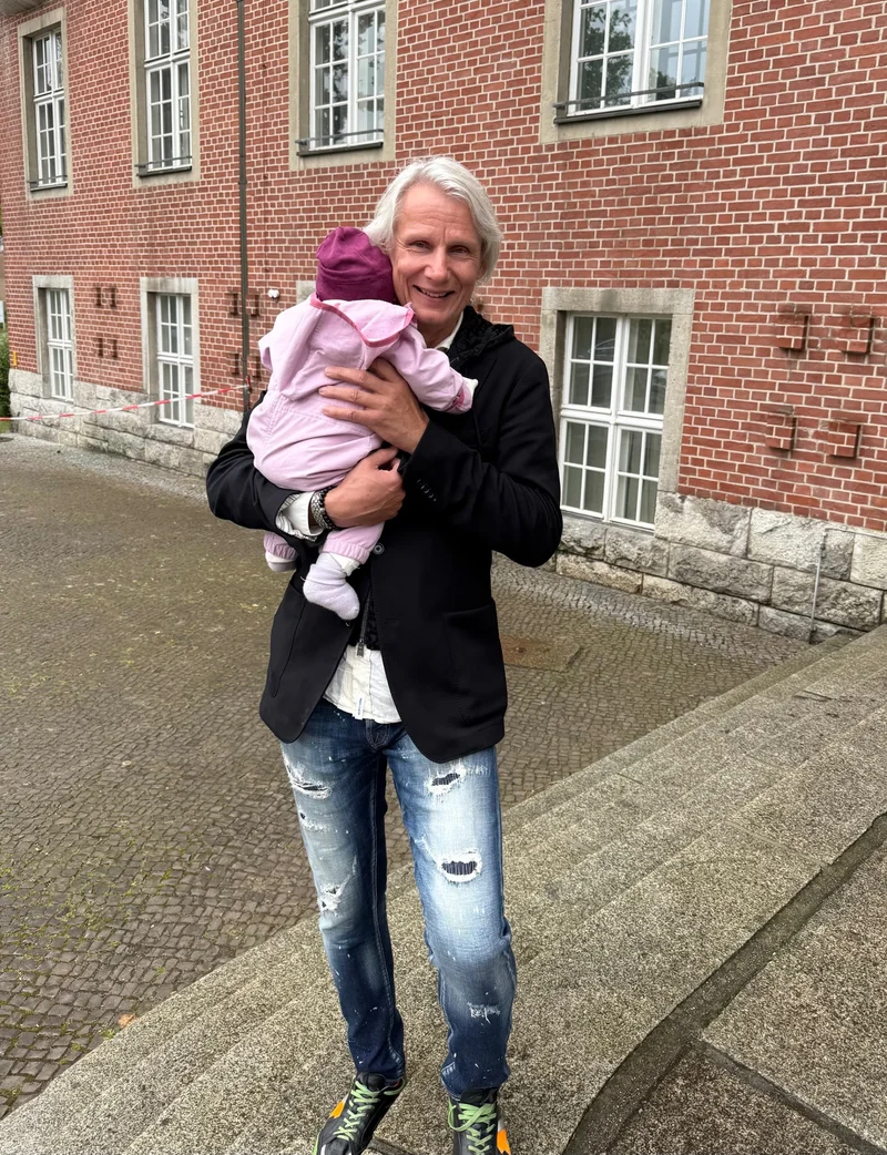 Karsten hält ein Kind, dessen Gesicht von der Kamera abgewandt ist