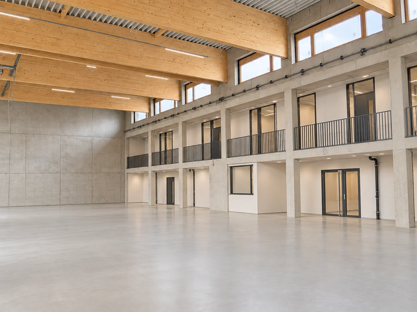 Fertig ausgebaute Halle mit Holzträgern, verglasten Räumen und freier Bodenfläche – KI-visualisiertes Beispielmotiv